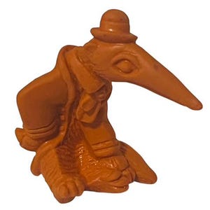 Könnte beinhalten: Eine kleine, braune Keramikfigur eines Vogels mit Hut. Der Vogel hat einen langen Schnabel und sitzt auf seinen Beinen. Die Figur ist detailliert und hat einen rustikalen Look.