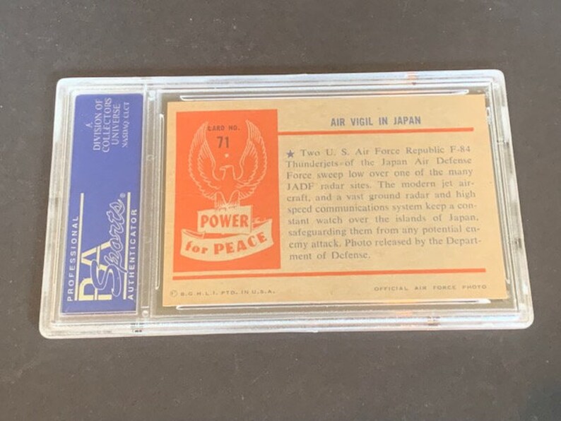 May include: A vintage trading card featuring a photo of two US Air Force Republic F-84 Thunderjets flying over a radar site in Japan. The card has a red, white, and blue design with the words "Power for Peace" and "Air Vigil in Japan".