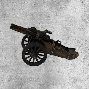 Puede incluir: Un modelo de cañón de metal negro con un cañón y ruedas de madera. El cañón está sobre un fondo gris.