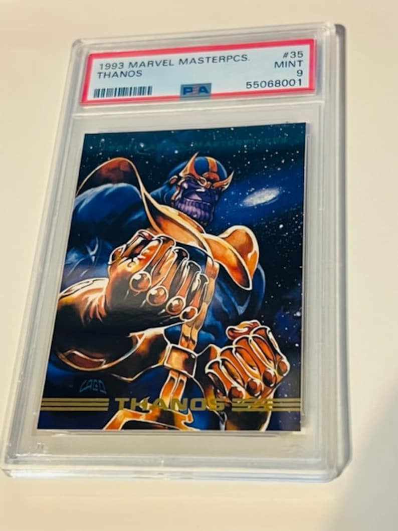 May include: A graded trading card featuring Thanos, a Marvel Comics character, in a purple and gold costume. The card is from the 1993 Marvel Masterpcs series and is graded Mint 9 by PSA. The card number is #35.