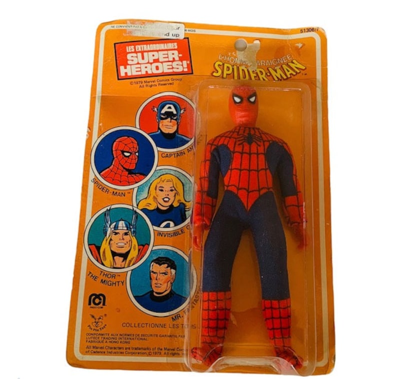 May include: A vintage action figure of Spider-Man in his red and blue suit with a black spider web design. The figure is packaged in a plastic blister pack with a yellow and orange cardboard backing. The back of the card features images of other superheroes, including Captain America, Thor, and the Invisible Woman. The card reads "Les Extraordinaires Super-Heroes!" and "L'Homme Araignee Spider-Man".