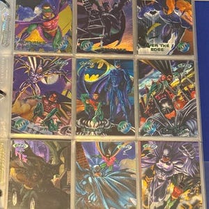 Könnte beinhalten: Neun Batman-Sammelkarten in einem Ordner. Die Karten zeigen verschiedene Illustrationen von Batman und Robin in Actionposen. Die Karten haben einen metallischen Glanz und befinden sich in Schutzhüllen. Einige Karten haben Text wie "Gotham's" und "Code Red".