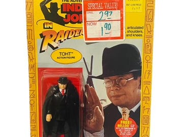 May include: A plastic action figure of Toht from the movie Raiders of the Lost Ark. The figure is wearing a black suit, a black fedora, and a black cape. The figure is posed with his arms at his sides. The figure is packaged in a yellow and red cardboard box with a picture of Toht on the front. The box also includes the text "The Adventures of Indiana Jones" and "Raiders of the Lost Ark".