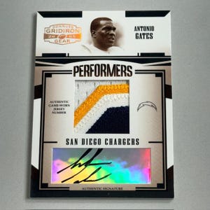 Op de afbeelding: Een Donruss Gridiron Gear trading card met Antonio Gates. De kaart bevat een game-worn jersey patch met gele, witte en marineblauwe accenten. De kaart heeft ook een authentieke handtekening en het San Diego Chargers logo.
