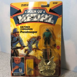 May include: A Men of Medal toy soldier set featuring an Air Force Commando Paratrooper. The set includes a plastic action figure, a medal, and a badge. The packaging features a cartoon image of soldiers in action.