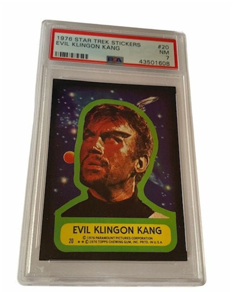 Pu&ograve; includere: Un adesivo vintage di Star Trek con un primo piano del personaggio "Evil Klingon Kang" della serie di chewing gum Topps del 1976. L'adesivo &egrave; su uno sfondo spaziale blu scuro con stelle e un pianeta.