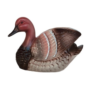 May include: A ceramic duck figurine with a brown and white patterned body and a red head. The duck is in a swimming position with its head turned to the side.