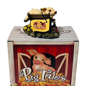 May include: A pink pig figurine sitting on a wooden ladder with a yellow sign that says "Pig Tales by Country Artists". The figurine is sitting on a base with green grass and flowers.