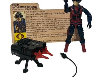Puede incluir: Una figura de acción Cobra Anti-Armadura Especialista de color negro y rojo con un vehículo de destrucción de tanques negro y rojo. La figura sostiene un arma negra y lleva un casco rojo con una visera negra. El vehículo tiene un cuerpo negro con misiles rojos y una base negra. La figura y el vehículo están sobre un fondo blanco. La tarjeta dice "COBRA ANTI-ARMOR SPECIALIST Code Name: SCRAP-IRON File Name: Classified Primary Military Specialty: Tank Destroyer Birthplace: Classified"