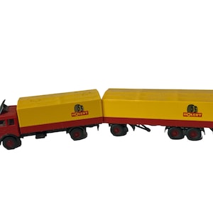 Könnte beinhalten: Ein roter und gelber Spielzeug-LKW mit Anhänger. Der LKW und der Anhänger sind beide mit "Holleyt" und einem Reifenlogo beschriftet.