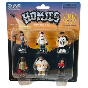 May include: A plastic package containing six small figurines of people. The figures are part of the Homies series #13, a 10-year anniversary release. The figures are all wearing different clothes and have different hairstyles. The package is on a black background.