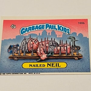 May include: A Garbage Pail Kids trading card showing a cartoon character called Neil lying on a bed of spikes. The card is pink, blue and yellow with the text "NAILED NEIL" and "GARBAGE PAIL KIDS" on it.