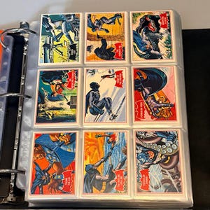 Könnte beinhalten: Ein Ordner mit Vintage-Batman-Sammelkarten. Die Karten zeigen farbenfrohe Comic-Illustrationen von Batman, Schurken und Action-Szenen. Jede Karte hat einen roten Rand und Text mit verschiedenen Titeln.