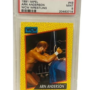 Puede incluir: Una tarjeta coleccionable de 1991 Impel Arn Anderson WCW Wrestling, calificada por PSA. La tarjeta presenta una imagen en color de Arn Anderson en acción, sobre un fondo amarillo con un borde negro y rojo. La tarjeta está dentro de un soporte protector transparente.