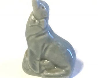 May include: A gray ceramic figurine of a seal wearing a bow tie. The seal is sitting upright with its head tilted up.
