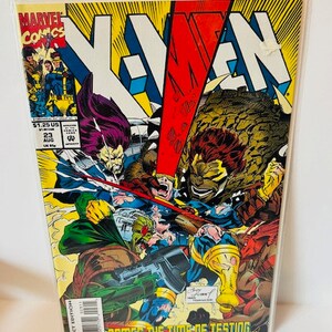 Könnte beinhalten: Ein Comic-Cover mit den X-Men, in einem rot-blauen Farbschema. Das Cover zeigt den Text "X-Men" in großen, fetten Buchstaben. Die Charaktere auf dem Cover sind Wolverine, Cyclops und Beast. Das Cover zeigt auch den Text "Comes the time of testing..."