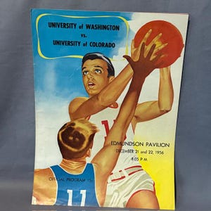 Könnte beinhalten: Vintage Basketball-Programmcover mit einem Spieler, der nach einem roten Basketball greift. Der Text lautet "University of Washington vs. University of Colorado" und "Edmundson Pavilion, 21. und 22. Dezember 1956, 20:05 Uhr."