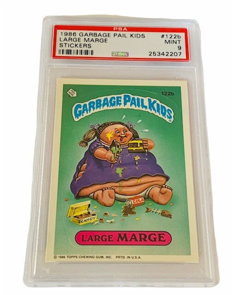 Puede incluir: Una tarjeta de intercambio de Garbage Pail Kids calificada que presenta a Large Marge, un personaje con un vestido morado y una cara sucia, rodeado de dulces y otros art&iacute;culos. La tarjeta est&aacute; calificada con un 9 por PSA y tiene el n&uacute;mero #122b.