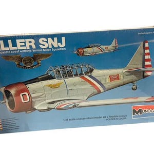 May include: A model kit of a white and red Miller SNJ aircraft with the words "Miller SNJ" and "As seen coast to coast with the famous Miller Squadron" on the box. The box also includes the text "1/48 scale unassembled model kit - Modele réduit - MOLDED IN COLOR" and "Includes parts for one aircraft".