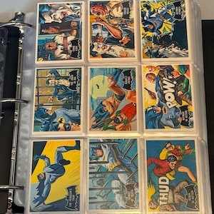 Könnte beinhalten: Neun Vintage Batman Sammelkarten in einem Ordner. Die Karten zeigen farbenfrohe Illustrationen von Batman, Robin und verschiedenen Bösewichten in Action-Szenen. Text auf den Karten enthält "POW", "THUD" und Titel wie "The Penguin's Trap."