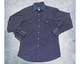 May include: A long-sleeved button-down shirt with a striped pattern in navy blue, red, and tan. The shirt has two chest pockets, a collar, and buttoned cuffs. The brand label "Wrangler" is visible.