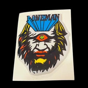 May include: A sticker with a colorful illustration of a face with a single eye and a beard. The word "ONEMAN" is written above the face.