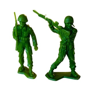 May include: Two green plastic toy soldiers, one standing at attention holding a rifle, the other aiming a rifle.