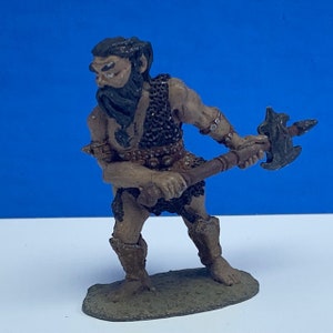 May include: A painted miniature figurine of a barbarian warrior with a beard, wearing chainmail and holding a large axe. The figurine is standing on a brown base.