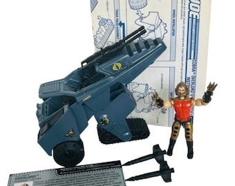May include: A blue and gray Cobra Overlord vehicle with a Cobra logo and a Cobra Commander figure. The vehicle has a large cannon and two smaller cannons. The figure is wearing a red and gold uniform and holding a gun. The image also includes instructions for assembling the vehicle.
