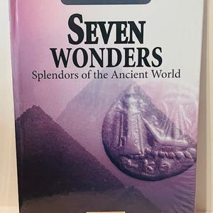 Könnte beinhalten: Ein DVD-Gehäuse mit einem violetten Hintergrund und einem Münzbild in der Mitte. Der Text auf dem Gehäuse lautet "Ancient Mysteries Seven Wonders Splendors of the Ancient World" und "Ancient Civilizations DVD Video".