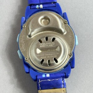 Puede incluir: Un reloj de pulsera azul con una correa azul. La esfera del reloj es plateada con el texto "&copy;2000-Zeeks Inc. WINTERLAND" y "&copy;2000 Trendmasters, Inc. MADE IN CHINA". La parte trasera del reloj es de acero inoxidable. Modelo #70156.