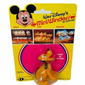 May include: A vintage Walt Disney's Mini Winders toy featuring Pluto, packaged on a yellow and pink card. The card includes images of Mickey Mouse, Donald Duck, and other characters. The packaging reads "Wind Up Action!" and "For Ages 3 and Over."