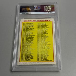 May include: A graded trading card featuring a Garbage Pail Kids 13th Series checklist. The card is encased in a clear plastic holder with a PSA label and serial number. The checklist includes various character names and card numbers.