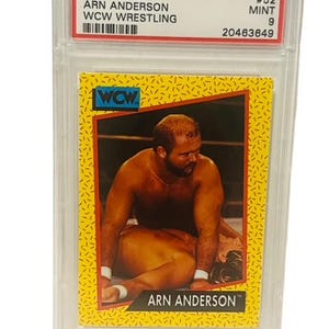 Puede incluir: Una tarjeta de intercambio de lucha libre WCW Impel de 1991 con Arn Anderson. La tarjeta está calificada como PSA 9 Mint. La tarjeta presenta una foto de Arn Anderson en un combate de lucha libre. La tarjeta es amarilla con detalles en blanco y negro.