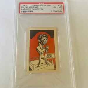 May include: A vintage trading card featuring a black and white illustration of a boxer in a boxing ring. The card is from the 1947 D. Cummings & Son Famous Fighters series and features Dado Marino. The card is graded NM-MT 8 by PSA and has the number 22665901.