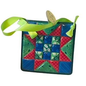 May include: A green, red and blue patchwork quilt block ornament with a green ribbon and a tag that says "Made with Love".