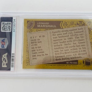 Op de afbeelding: Een vintage Topps voetbalkaart uit 1985 met Leonard Marshall, een voormalige NFL-defensive end. De kaart is in uitstekende staat en toont een foto van Marshall in zijn New York Giants-uniform. De kaart bevat ook Marshalls statistieken en een korte biografie.