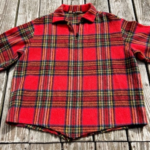 May include: A red and black plaid shirt with a collared neckline and a three-button placket. The shirt features a classic plaid pattern with yellow, green, and orange accents. The fabric appears to be a soft, woven material.