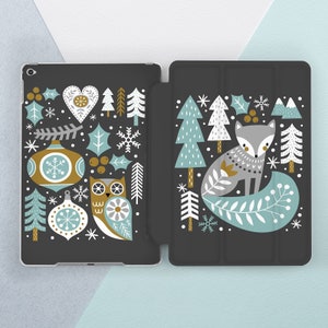 Puede incluir: Una funda de teléfono negra con un diseño de temática invernal que presenta un zorro, un búho y adornos navideños. El diseño está en tonos de azul, verde, blanco y dorado.