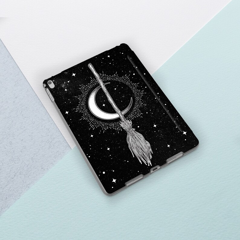 May include: Black iPad case with a white crescent moon and a broom with stars in the background.
