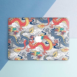 May include: A laptop skin with a colorful design featuring red, blue, and yellow dragons on a white background. The design is reminiscent of traditional Chinese art.