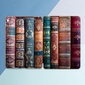 May include: A tablet case featuring a design of antique books with ornate gold detailing. The spines are various colors, including burgundy, teal, and brown. Some books have text that reads "VOL. II. HISTORIES," "HISTOIRE ANCIENNE," and "BRITISH NOVELISTS."