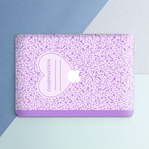 May include: A purple laptop skin with a composition notebook pattern and a heart-shaped sticker that says "COMPOSITION". The Apple logo is visible on the skin.