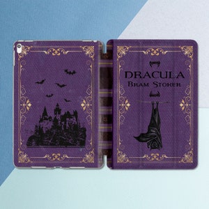 Puede incluir: Una portada de libro púrpura y dorada con el título "Drácula" de Bram Stoker. La portada presenta una silueta negra de un castillo y un murciélago.