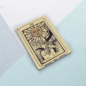 K&ouml;nnte beinhalten: Eine beige iPad-H&uuml;lle mit einer Vintage-Illustration der Tarotkarte Sonne. Die Karte zeigt eine Sonne mit einem Gesicht, ein Einhorn und den Text "The Sun" und "XIX".