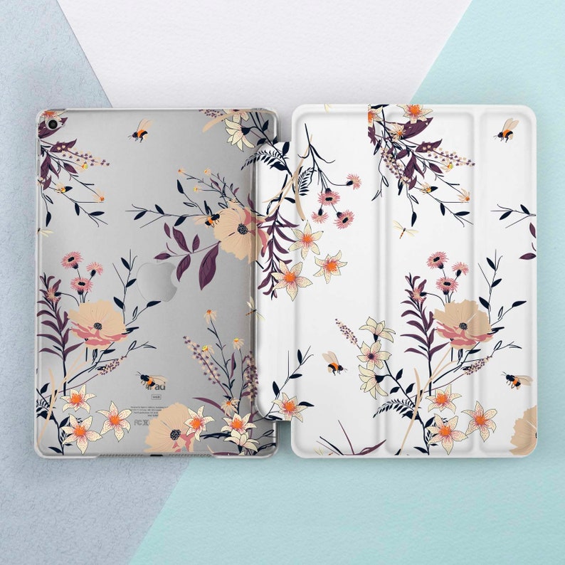 May include: A white and gray floral iPad case with a white floral design and a clear back. The case has a stand feature and is made of durable plastic.