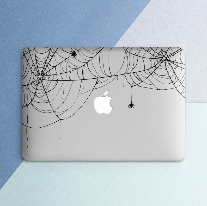 May include: A gray laptop computer with a black spiderweb design on the lid. The design features several spiders and dripping strands of web.