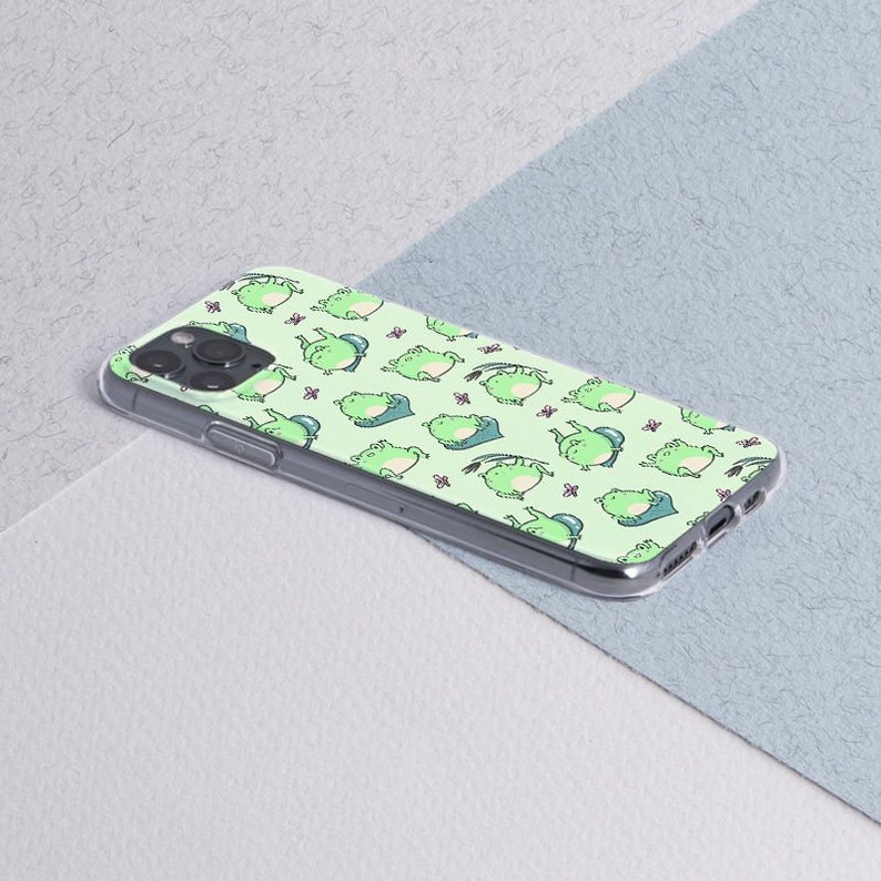 May include: A clear phone case with a green and white frog pattern. The case is designed for an iPhone.