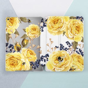 May include: A white and gray floral phone case with yellow roses and bumblebees. The case has a white background with a gray border.