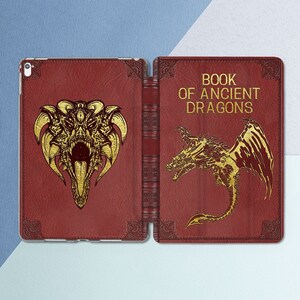 Könnte beinhalten: Ein roter Lederbuchumschlag mit goldenen Akzenten und einem Drachenmotiv. Der Umschlag trägt die Aufschrift "Book of Ancient Dragons".